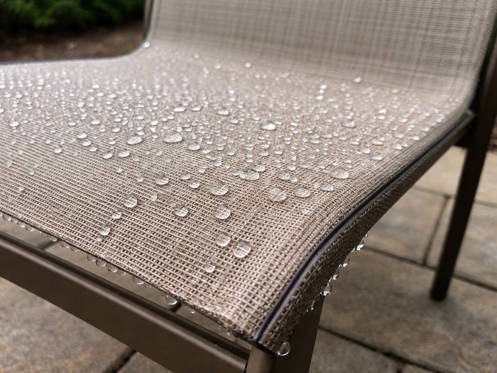 Sling patio chair fabric with water beading and quickly draining after rainfall.