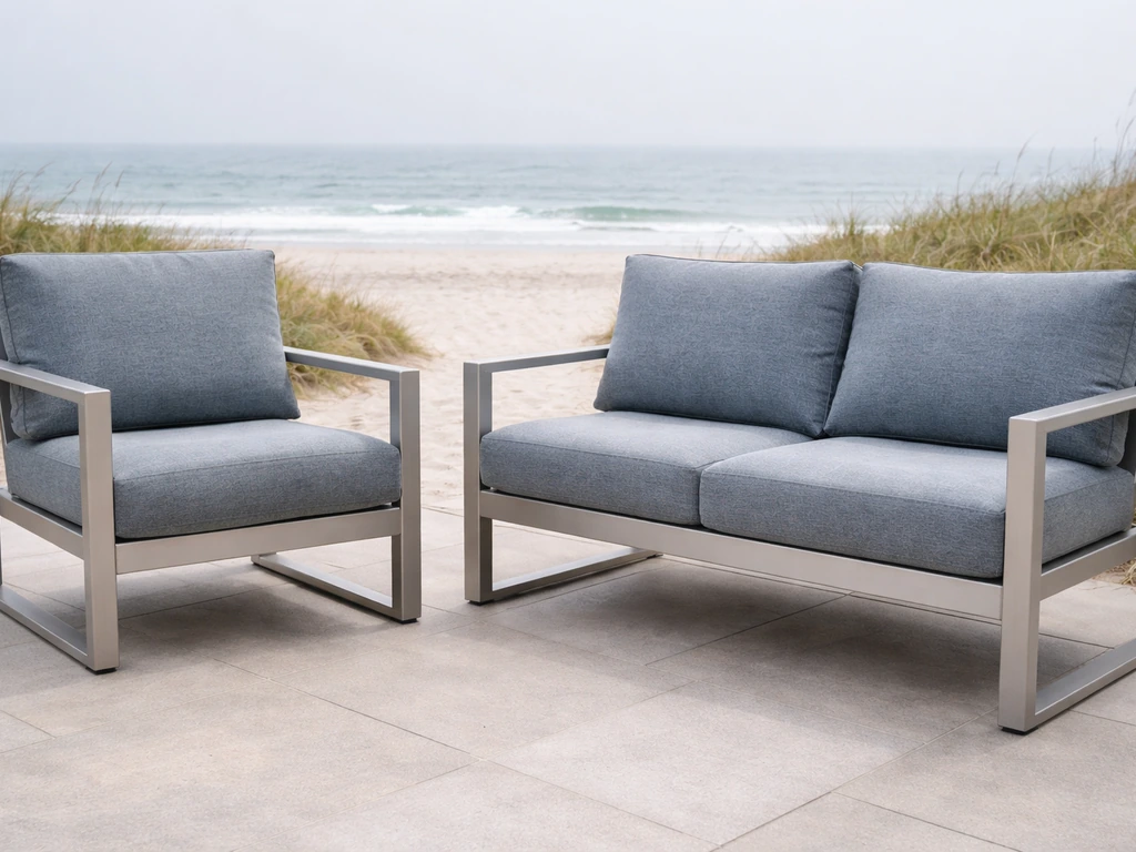 Coastal patio furniture with marine-grade metal frames and solution-dyed cushions near the ocean.