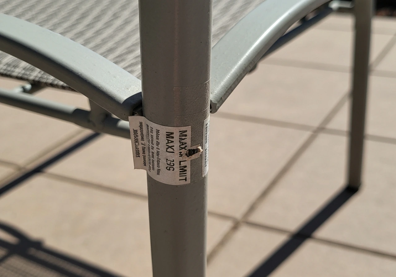 Close-up of a patio chair frame with a small weight-limit label near a metal joint.